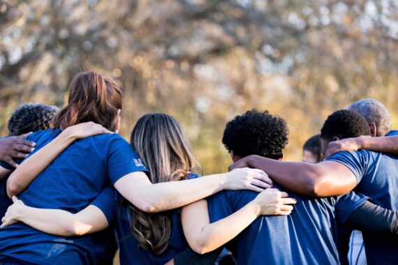 group of people outside in blue tshirts in a huddle.